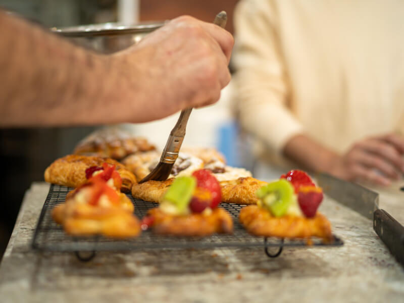 Hands brushing pastries in a French baking class